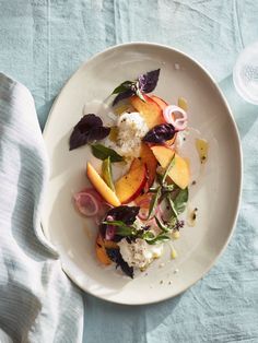 a white plate topped with fruit and veggies on top of a blue table cloth