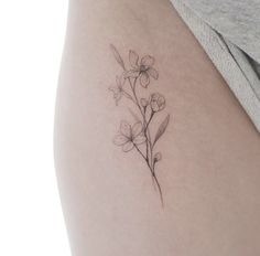 a woman's thigh with a small flower tattoo on the back of her leg