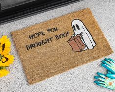 a door mat that says, hope you brought boo on it next to sunflowers