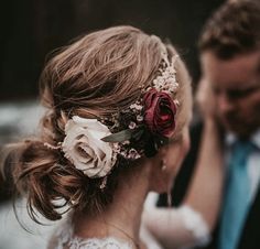 a bride and groom standing next to each other in front of a waterfall with flowers on their hair