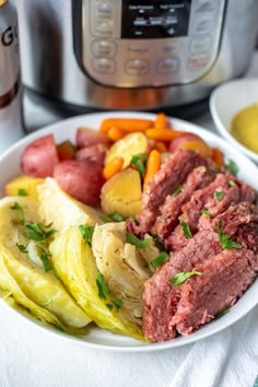 corned beef, cabbage and carrots on a plate next to an instant pot roast