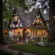 a house that is lit up with lights and flowers in the front yard at night