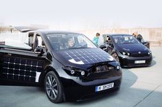 an electric car with solar panels on the roof is parked in front of other cars