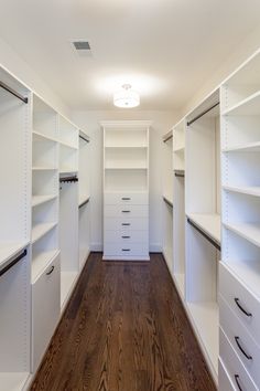 an empty walk - in closet with white shelves and drawers on the wall, along with wooden flooring