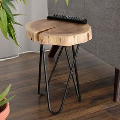 a remote control sitting on top of a wooden table next to a chair and potted plant