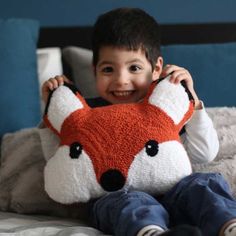 a young boy holding a stuffed animal on top of a bed