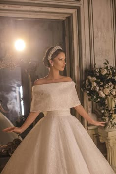 a woman in a white wedding dress standing next to a mirror with her hands on her hips