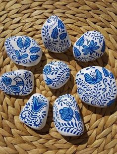 blue and white painted rocks sitting on top of a woven basket