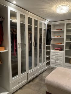 a walk in closet filled with lots of white drawers and shelves next to a bed