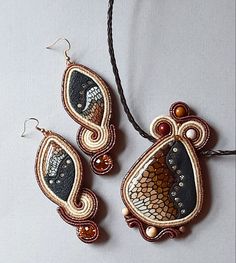 two pieces of beaded jewelry hanging from a cord on top of a white surface