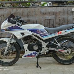 a white and blue motorcycle parked next to a fence