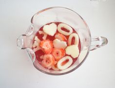 a cup filled with liquid and cut up fruit in the shape of heart shaped letters