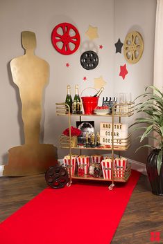 a red carpet in front of a table with drinks and snacks on it, next to a gold statue