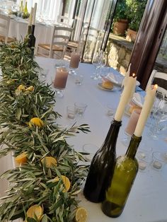 two wine bottles sitting on top of a table next to some lemons and candles