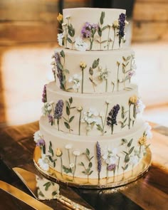 a wedding cake decorated with flowers and greenery on a wooden table next to scissors