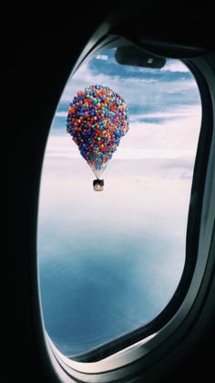 an airplane window with a colorful balloon floating in the sky from it's seat