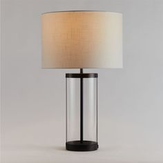 An illuminating mix of modern design and timeless craft, our Promenade table lamp showcases its crisp black accents in a cylinder of hand-blown glass. Slim circles of black iron cap the tall base, and a white linen drum shade adds textural counterpoint. Designed for modern living, each lamp also features a handy USB port on the base to keep devices charged and ready. Striking on its own or paired with the coordinating floor lamp, our Promenade table lamp is a Crate & Barrel exclusive.     Hand-b Tall Table Lamps Usb, Black Lamp With White Shade, Modern Bedside Table Lamps Black, Glass And Black Table Lamp, Affordable Black Metal Table Lamp, Dining Room Table Lamps, Lamp With Usb Port, Table Lamp Black Contemporary, Nyc Rooms