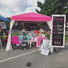 a pink and white tent set up in the middle of a parking lot next to tables with chairs under it