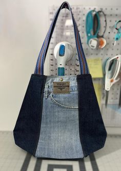 a purse made out of jeans hanging on a wall with earphones and hairdryers