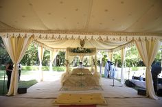 an outdoor wedding ceremony setup with white drapes and yellow linens on the ground