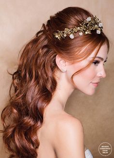 a woman with long red hair wearing a gold headpiece and flowers in her hair