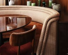 a curved table with chairs and vases on it