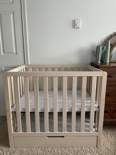 a baby crib in the corner of a room with a mirror on the wall