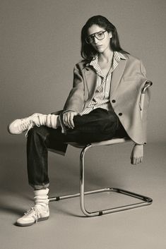 a black and white photo of a woman sitting on a chair with her legs crossed