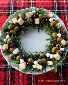 olives, cheese and rosemary wreath on a white platter with red plaid tablecloth