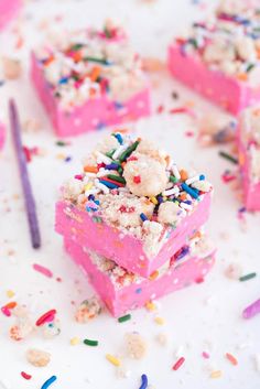 pink cake with sprinkles and confetti on top sitting on a table