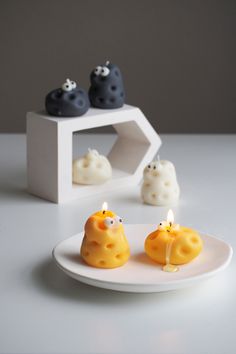 two candles with faces on them sitting on a white plate next to some other items