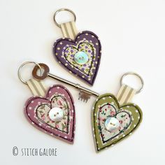 three heart shaped keychains with buttons on them