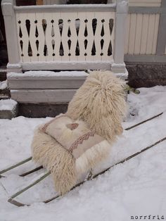 a stuffed animal sitting on top of snow covered ground next to a bench and railing