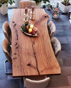 a wooden table with candles on it in a room filled with plants and potted plants