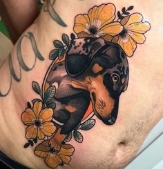 a woman's stomach with a dachshund tattoo on it and flowers