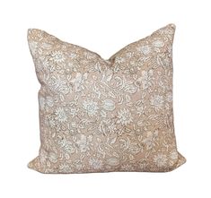 a beige and white pillow with an intricate design on the front, sitting against a white background