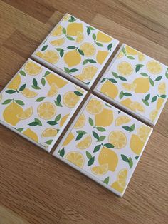 four coasters with lemons on them sitting on top of a wooden table next to each other