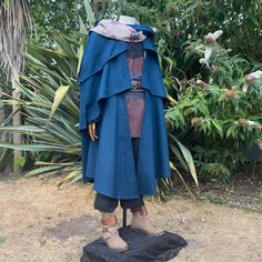 "LARP Costume Set Spellcaster includes Three Layer Cloak in Teal, Shirt in Brown and Black, and Buffalo Leather Belt in Black. LARP Cloak: Cloak with three layers of wool cape and elaborately patterned lining designed to flow majestically as you move around. Slits on the sides of the layered capes allow hints of lining to show through, even with subtle movements. The large hood and built-in scarf are also lined with the same patterned lining, which can be wrapped around the neck and draped to th Medieval Cape For Larp In Fall, Elven Cape Outerwear For Cosplay, Elven Cosplay Cape Outerwear, Ren Faire Wedding, Hooded Medieval Cape For Larp, Medieval Long Sleeve Cape For Larp, Cloak Pattern, Wool Cape, Larp Costume