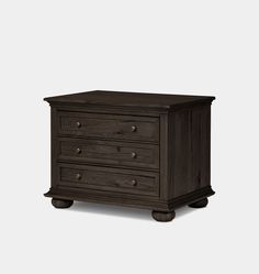 a dark wood dresser with three drawers and wheels on the bottom, in front of a white background