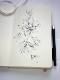 an open notebook with a drawing of a flower on it and a pen next to it