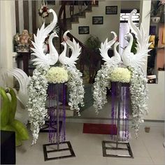 two tall vases with flowers and white birds on them in front of a mirror