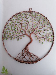 a wire tree with green leaves in the shape of a circle on a white background