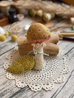 some crafting supplies are sitting on a doily next to wood sticks and yarn