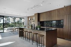 a kitchen with wooden cabinets and stools next to an open floor plan that looks out onto the outdoors