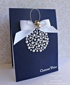 a christmas ornament is hanging from the side of a blue card with white ribbon