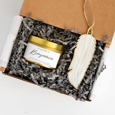 an open box containing a candle and a feather ornament with a label on it