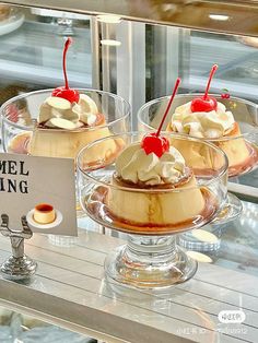 three desserts in glass dishes on display at a bakery window with a sign that says camell dining