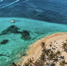 an aerial view of the beach and ocean with people swimming in the clear blue water