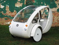 an unusual car is parked in front of a brick wall