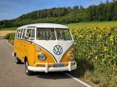 an old vw bus is parked on the side of the road in front of sunflowers